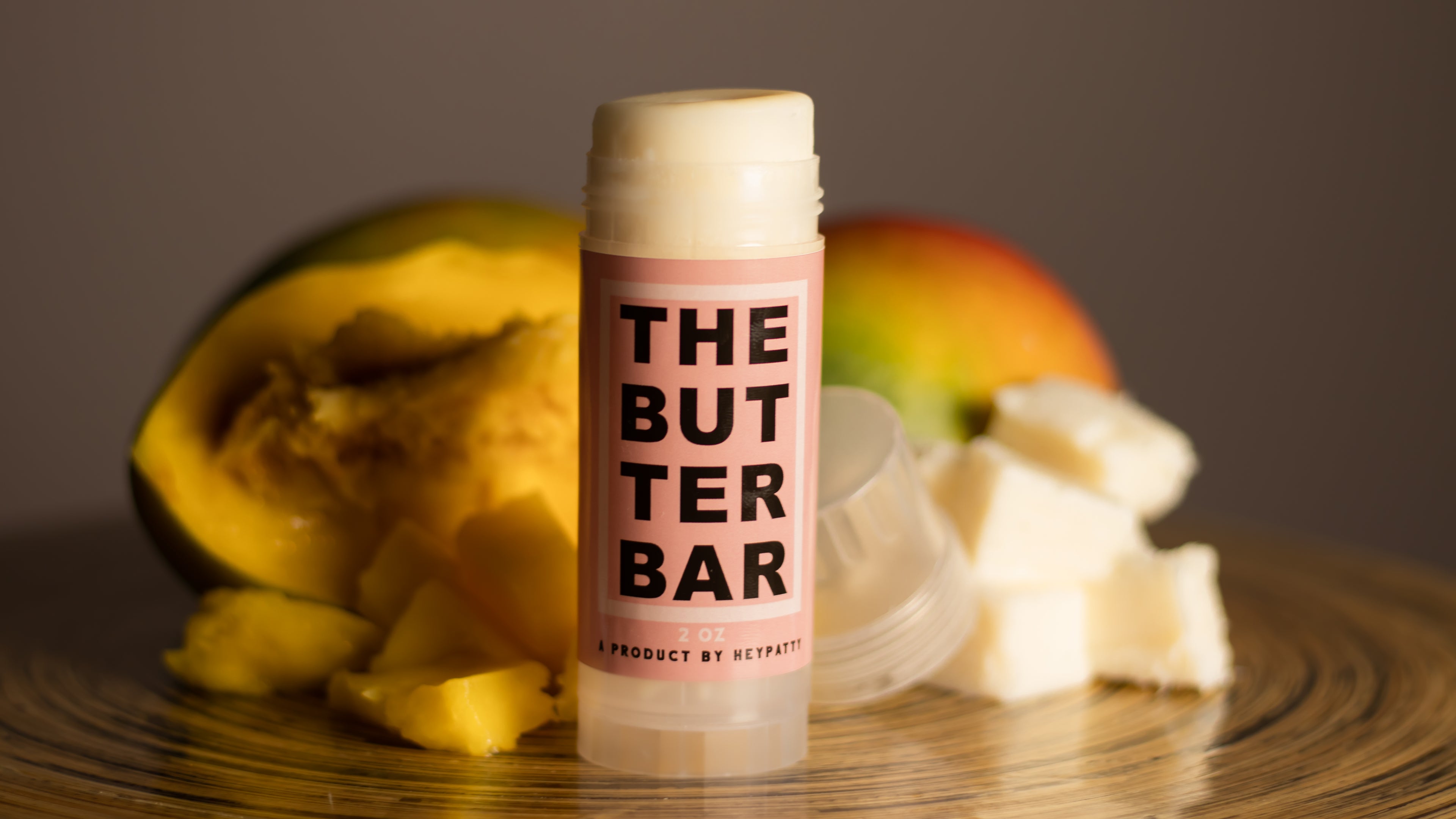 The Butter Bar skincare product displayed with fresh mango and raw mango butter, highlighting natural, nourishing ingredients.