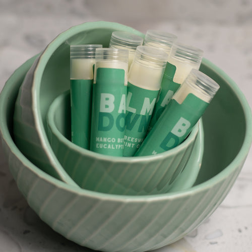 Green all natural lip balm tubes in a matching green bowl