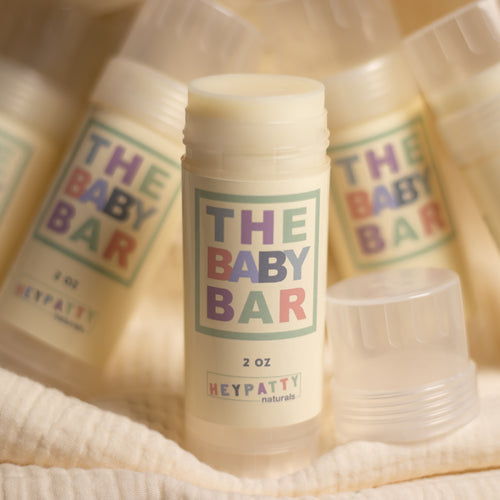 The Baby Bar natural solid moisturizer by Heypatty Naturals displayed together in soft, warm lighting