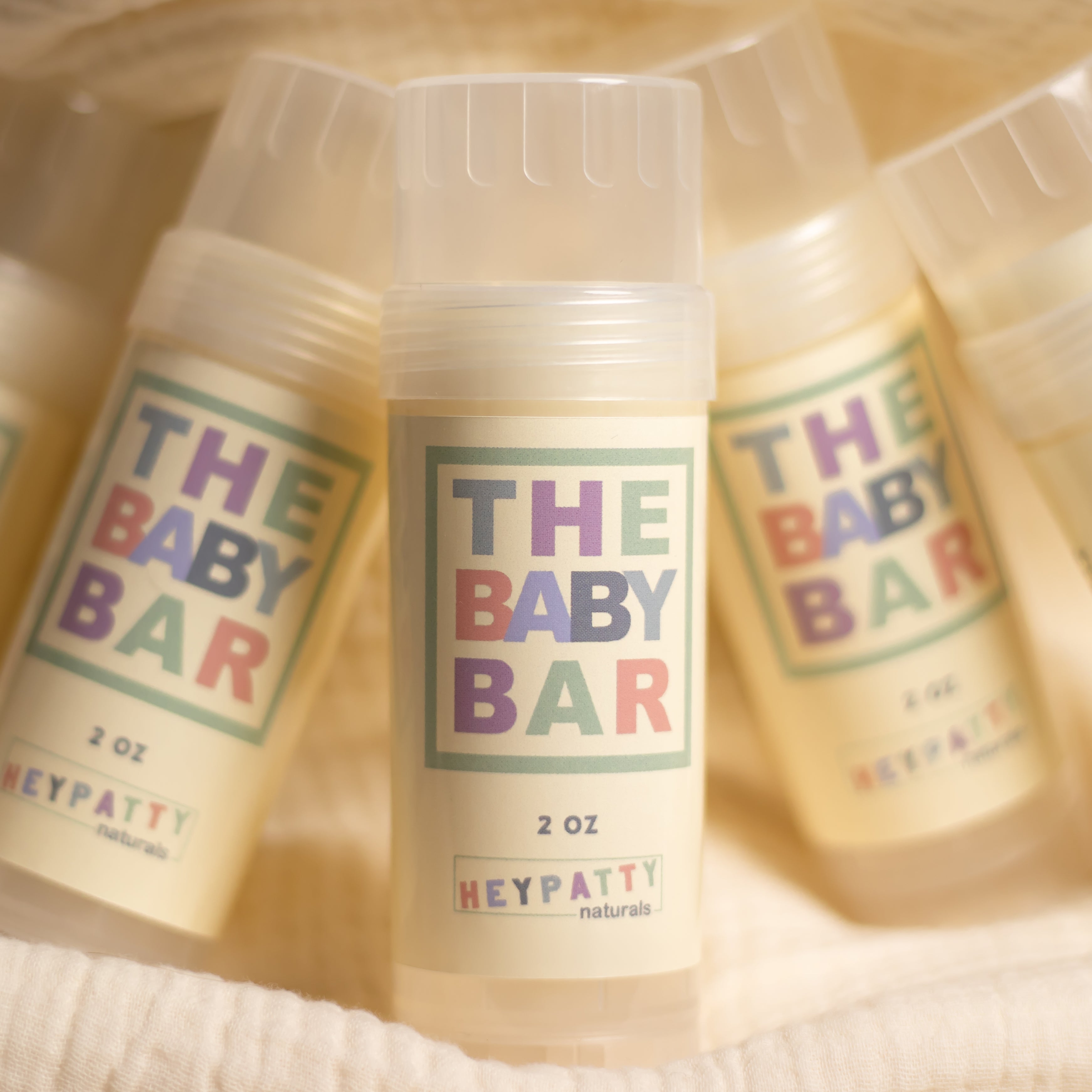 Bottles of 'The Baby Bar' by HEYPATTY Naturals on a soft beige background